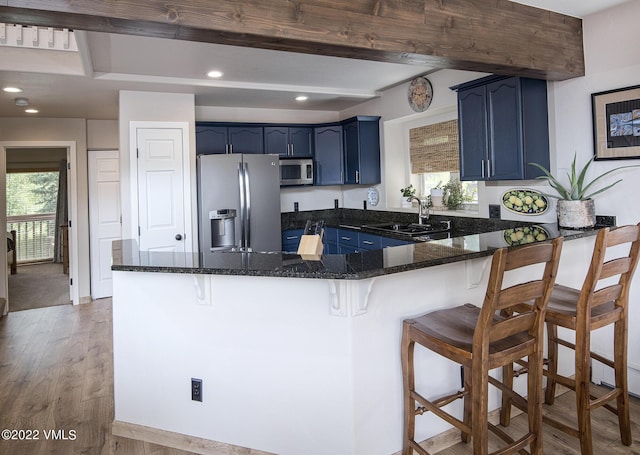 kitchen featuring blue cabinetry, a healthy amount of sunlight, a peninsula, stainless steel appliances, and a sink