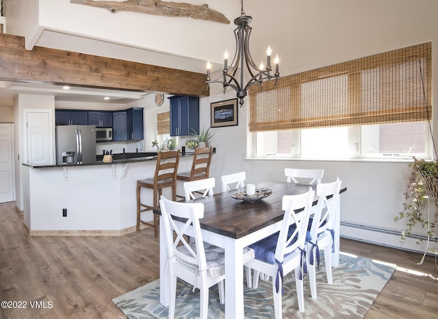 dining area with beam ceiling, a notable chandelier, a baseboard heating unit, and light wood-style floors