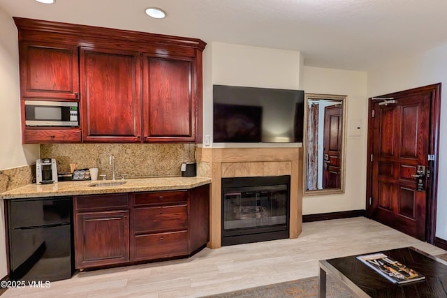 26 Avondale Ln Unit 104-H, Beaver Creek, CO 81620 - kitchen with stainless steel microwave, a sink, reddish brown cabinets, backsplash, and light stone countertops
