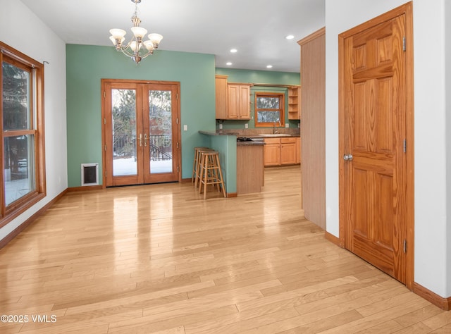 kitchen featuring a kitchen bar, sink, kitchen peninsula, hanging light fixtures, and french doors