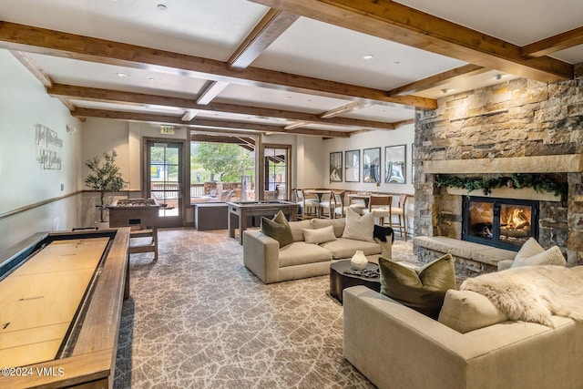 living room featuring beamed ceiling and a stone fireplace