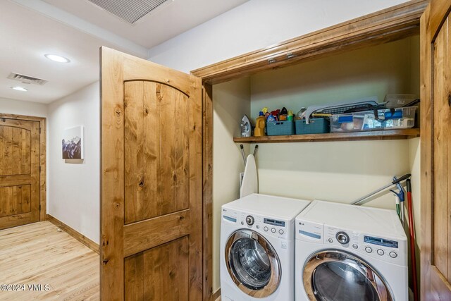 clothes washing area featuring washing machine and clothes dryer and light hardwood / wood-style flooring