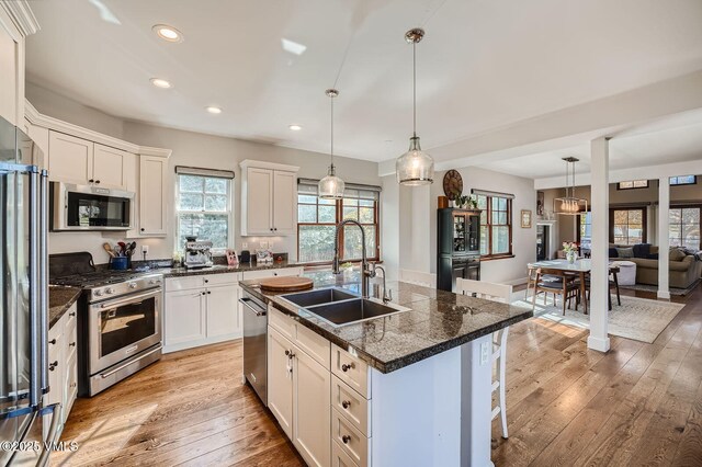 50 Bunker Way, Eagle, CO 81631 - kitchen featuring light wood finished floors, dark countertops, appliances with stainless steel finishes, a sink, and a kitchen breakfast bar