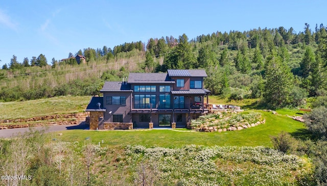 620 Jouflas Ranch Rd, Wolcott, CO 81655 - rear view of property with a wooded view, a yard, a standing seam roof, stone siding, and a metal roof