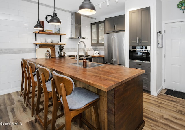 175 Hurd Ln Unit 3101, Avon, CO 81620 - kitchen featuring stainless steel appliances, wooden counters, wall chimney exhaust hood, wood finished floors, and glass insert cabinets