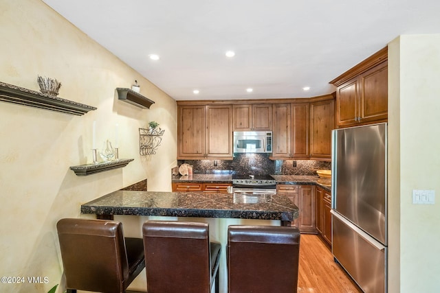 411 Eagle Dr Unit 10, Eagle-Vail, CO 81620 - kitchen featuring appliances with stainless steel finishes, a breakfast bar area, a peninsula, decorative backsplash, and tile counters