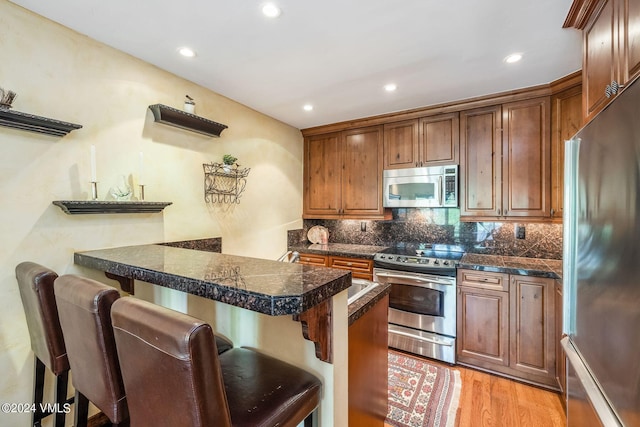 411 Eagle Dr Unit 10, Eagle-Vail, CO 81620 - kitchen featuring appliances with stainless steel finishes, a kitchen breakfast bar, a peninsula, tasteful backsplash, and light wood-style flooring
