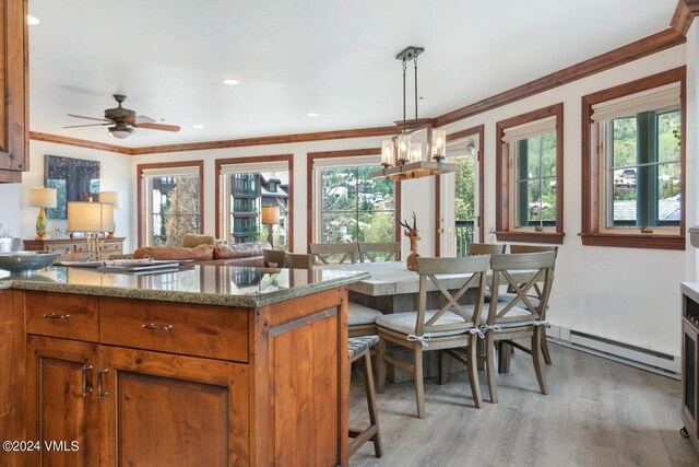 kitchen with pendant lighting, a wealth of natural light, light stone countertops, and a baseboard heating unit