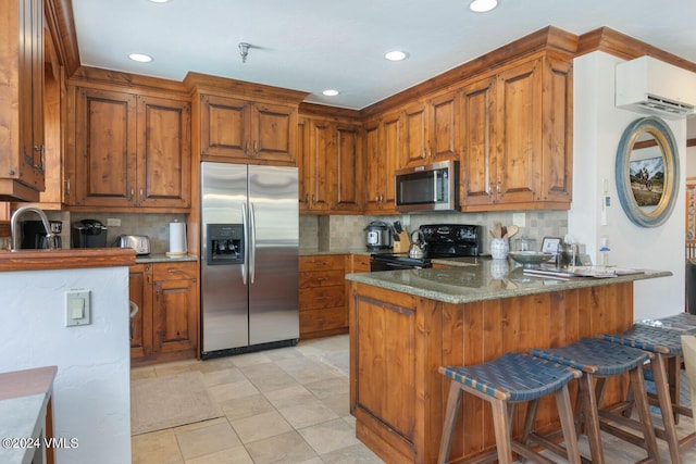 kitchen featuring a breakfast bar, a wall unit AC, stainless steel appliances, light stone counters, and kitchen peninsula