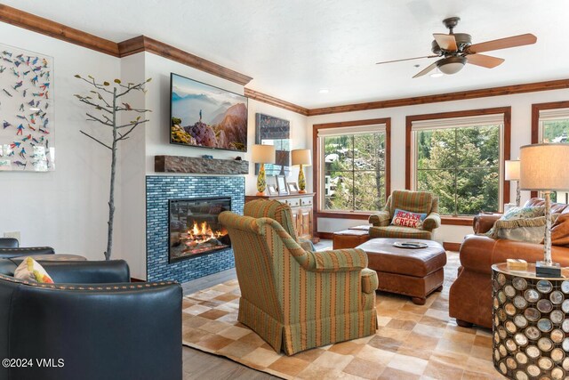 living room featuring crown molding, ceiling fan, and a tile fireplace