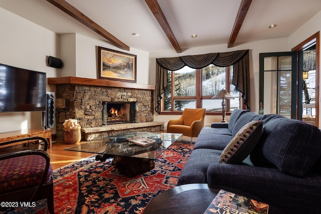 living room with recessed lighting, beamed ceiling, a stone fireplace, and wood finished floors