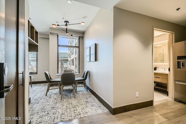 126 Riverfront Ln Unit 438, Avon, CO 81620 - dining space with light wood-type flooring, a chandelier, and baseboards