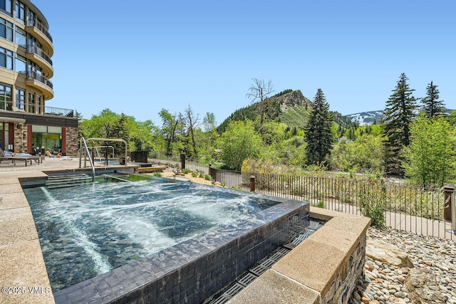 126 Riverfront Ln Unit 438, Avon, CO 81620 - view of pool featuring an outdoor hot tub, fence, a patio, and a mountain view