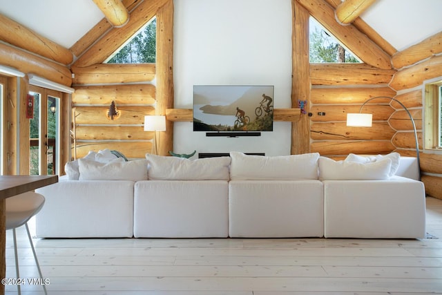 living room featuring plenty of natural light, light hardwood / wood-style floors, and vaulted ceiling with beams