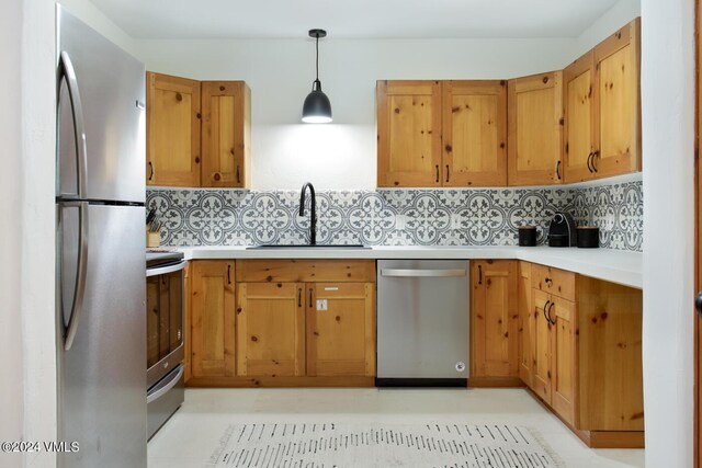 kitchen featuring pendant lighting, sink, decorative backsplash, and appliances with stainless steel finishes