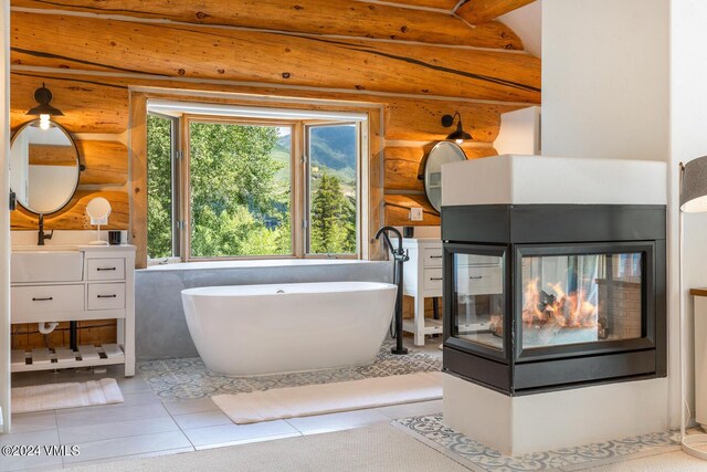 bathroom with tile patterned floors, vanity, a bathtub, and a multi sided fireplace