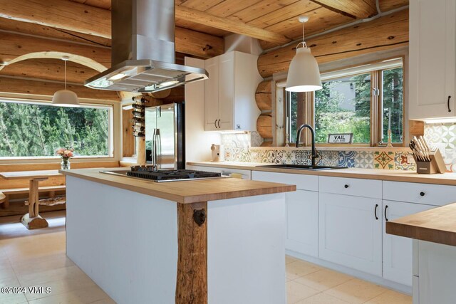 kitchen featuring white cabinetry, a center island, wooden counters, and appliances with stainless steel finishes