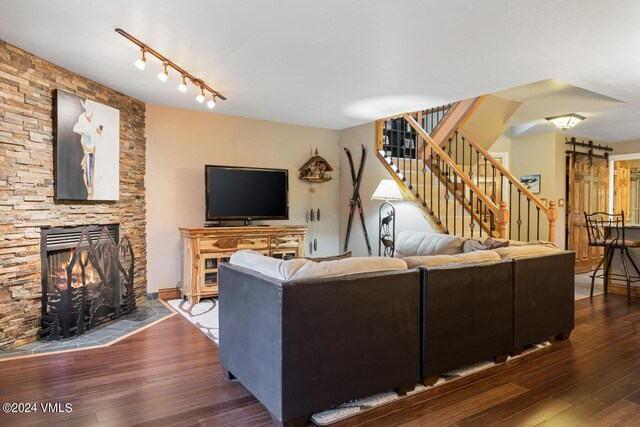 living room with dark hardwood / wood-style floors and a stone fireplace