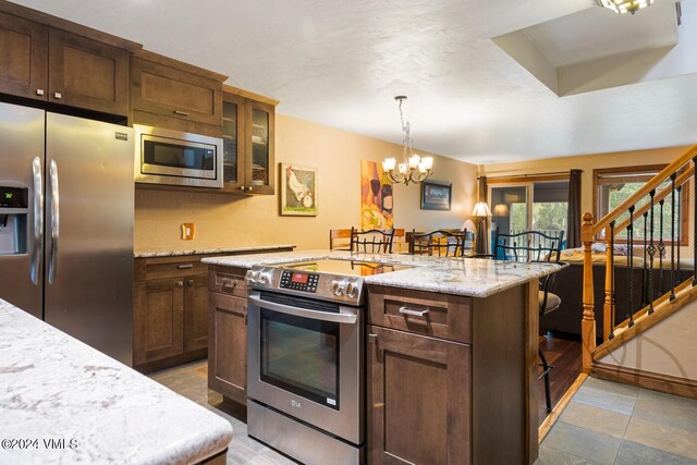 kitchen featuring a breakfast bar, decorative light fixtures, a chandelier, light stone counters, and stainless steel appliances