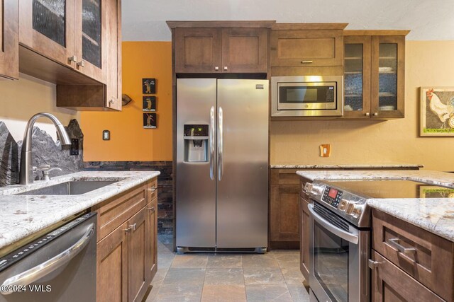 kitchen with stainless steel appliances, sink, and light stone counters