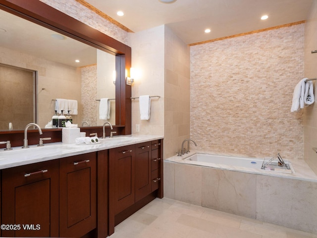 bathroom with tile walls, a garden tub, double vanity, and a sink