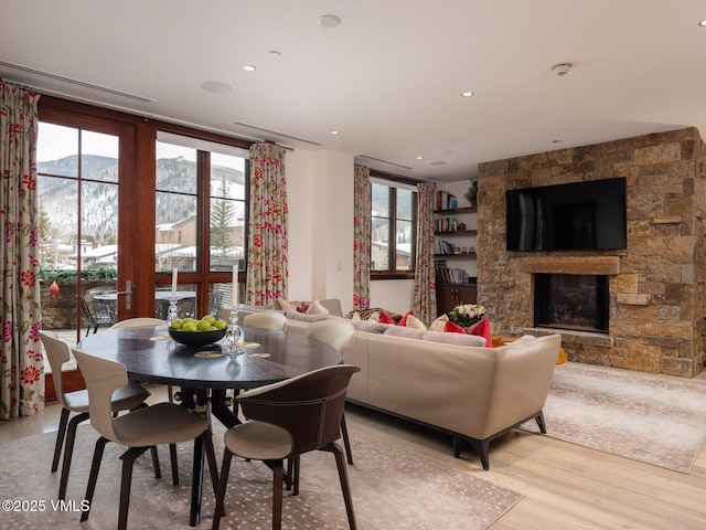 dining area featuring a wealth of natural light, a mountain view, light wood-style floors, and a fireplace