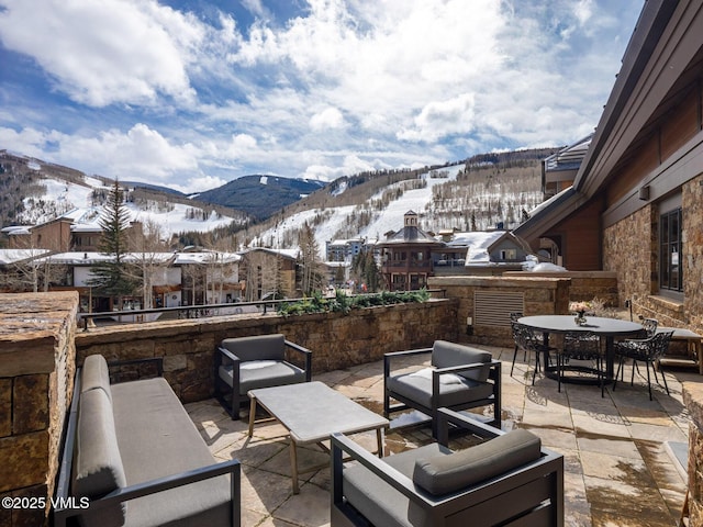 snow covered patio with a mountain view and outdoor dining space