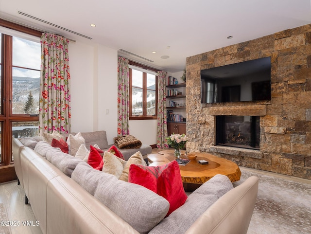 living room featuring a stone fireplace and wood finished floors