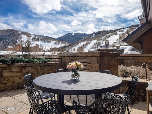 snow covered patio featuring outdoor dining area and a mountain view