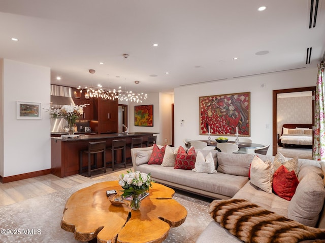 living area with recessed lighting, baseboards, a notable chandelier, and light wood finished floors