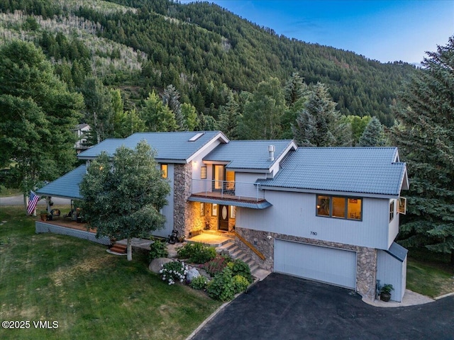 780 Deer Blvd, Avon, CO 81620 - view of front facade featuring a wooded view, stone siding, a balcony, and an attached garage