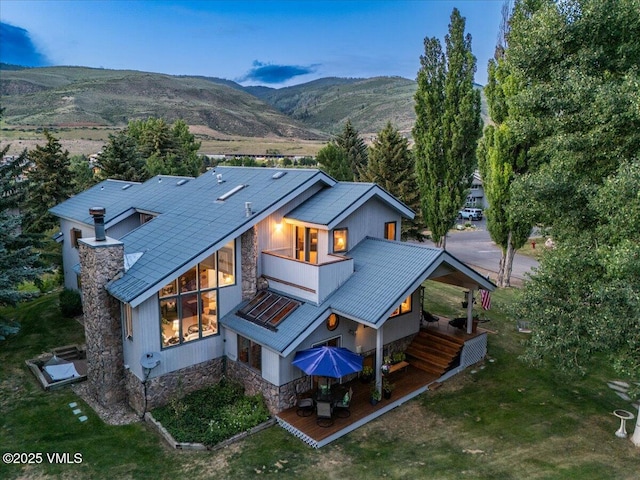 780 Deer Blvd, Avon, CO 81620 - rear view of property featuring a balcony, stone siding, a mountain view, and a lawn