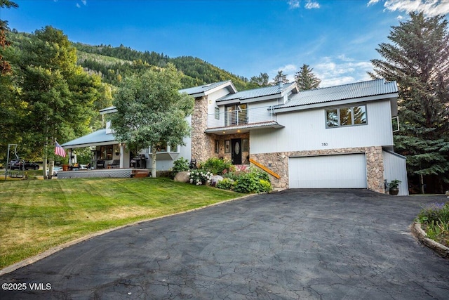 780 Deer Blvd, Avon, CO 81620 - view of front facade with stone siding, asphalt driveway, an attached garage, a chimney, and a balcony