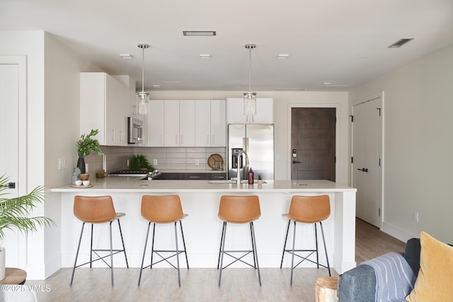 430 S Frontage Rd E Ru-D, Unit Ru-D Vail, CO 81657 - kitchen with stainless steel appliances, a peninsula, tasteful backsplash, a kitchen breakfast bar, and light wood-style floors