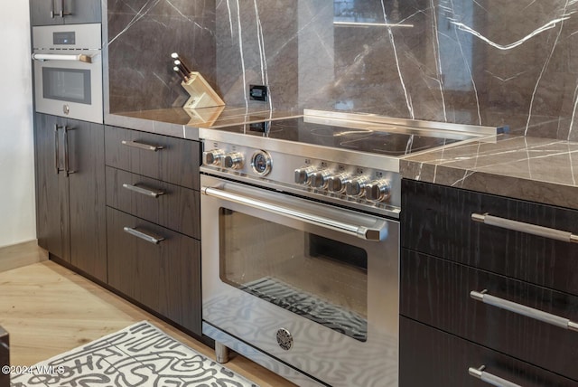 kitchen with dark brown cabinetry, stainless steel appliances, and light hardwood / wood-style floors