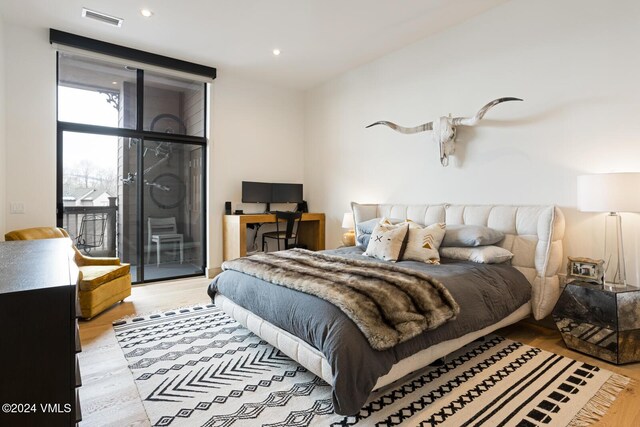 bedroom featuring access to exterior, a wall of windows, and light hardwood / wood-style floors