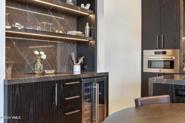 bar featuring backsplash, beverage cooler, and stainless steel oven