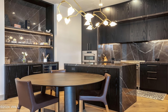 kitchen featuring wine cooler, decorative backsplash, a notable chandelier, stainless steel appliances, and light hardwood / wood-style flooring