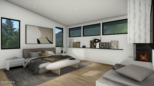 bedroom with lofted ceiling, multiple windows, a fireplace, and wood finished floors