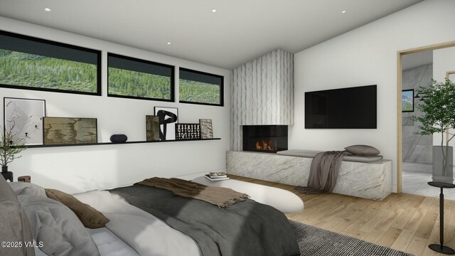 bedroom with light wood-type flooring, ensuite bath, and a fireplace