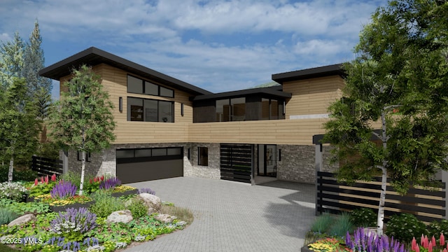 contemporary house featuring a garage, stone siding, and decorative driveway