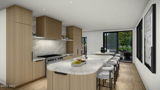 kitchen featuring a kitchen island with sink, modern cabinets, stainless steel range, and light wood finished floors