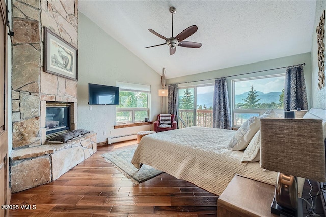 3078 Wildridge Rd Unit D, Avon, CO 81620 - bedroom featuring lofted ceiling, hardwood / wood-style floors, baseboard heating, a textured ceiling, and a fireplace
