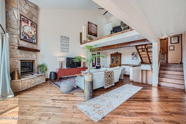 3078 Wildridge Rd Unit D, Avon, CO 81620 - living area featuring wood finished floors, stairs, a stone fireplace, a towering ceiling, and a textured ceiling