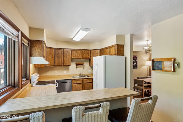 2540 Kinnikinnick Rd Unit G-2, Vail, CO 81657 - kitchen featuring white appliances, under cabinet range hood, a peninsula, and a breakfast bar area