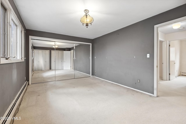 unfurnished bedroom featuring a closet, baseboards, a baseboard heating unit, and carpet flooring