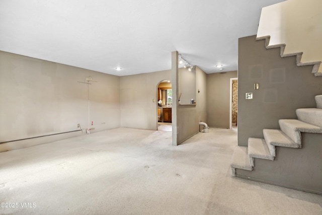 basement featuring carpet floors, arched walkways, and stairway