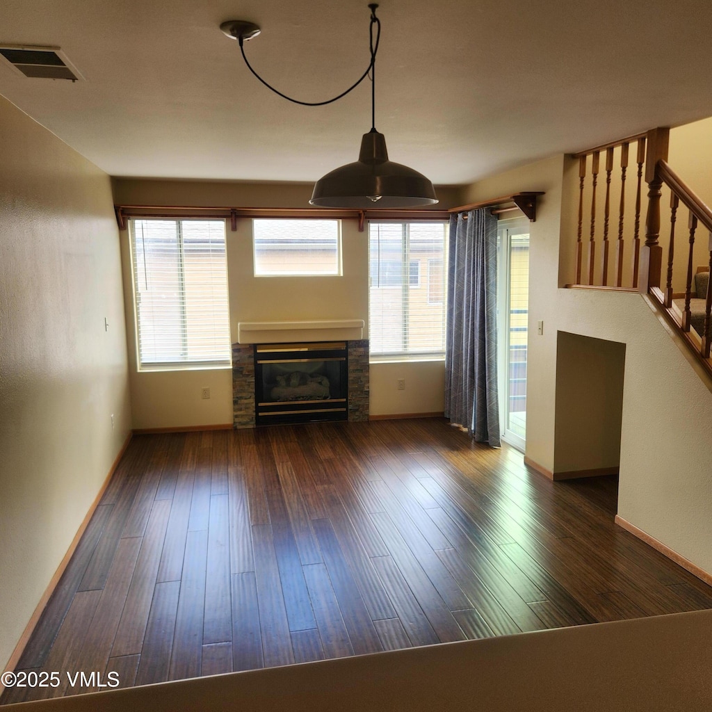 600 Nottingham Rd Unit 15, Avon, CO 81620 - unfurnished living room featuring a glass covered fireplace, baseboards, hardwood / wood-style flooring, and stairs
