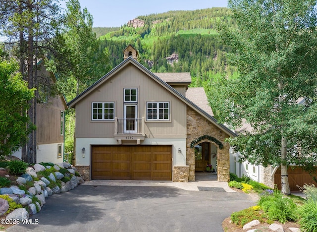 4240 Spruce Way, Vail, CO 81657 - view of front of home with stone siding, an attached garage, driveway, a forest view, and a chimney
