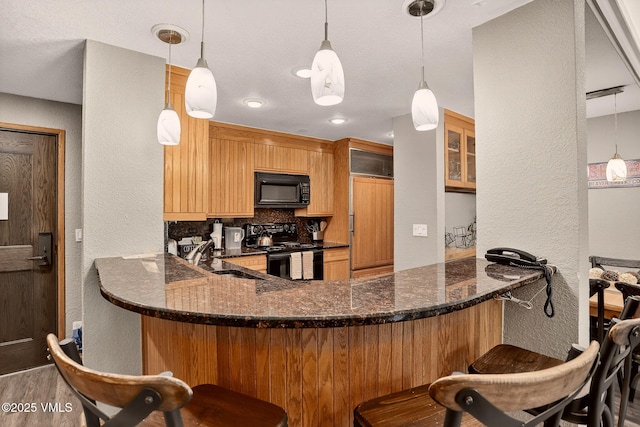 120 Offerson Unit 5160, Beaver Creek, CO 81620 - kitchen featuring black appliances, a textured wall, backsplash, a peninsula, and a kitchen bar